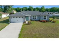 Charming single-story home features a manicured lawn, a two-car garage, and a light blue front door at 7886 Sw 103Rd Loop, Ocala, FL 34476