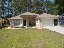 Charming single-story home featuring a well-manicured lawn and a two-car garage at 11653 Sw 72Nd Cir, Ocala, FL 34476