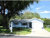 Charming single-story home with light blue siding, blue shutters, and mature trees at 12002 Sw 137Th Loop, Dunnellon, FL 34432