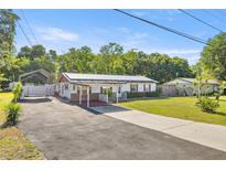 Wide shot of a single story home with solar panels, carport, and extended driveway at 12351 Se Hwy 464, Ocklawaha, FL 32179