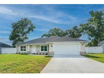 Charming single-story home with a well-manicured lawn, attached two-car garage, and a mix of stone and siding accents at 13588 Se 102Nd Ct, Belleview, FL 34420
