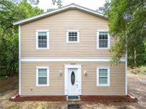 Charming two-story home featuring light beige siding, a white door with glass insert, and matching trim at 16295 W Highway 40, Ocala, FL 34481