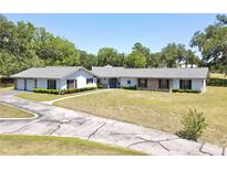 Sprawling ranch home with brick and white accents surrounded by lush greenery at 1711 Sw 63Rd St Rd, Ocala, FL 34476