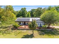 Charming home with a metal roof and solar panels, complemented by a well-manicured lawn and lovely landscaping at 18695 Ne 5Th Terrace Rd, Citra, FL 32113