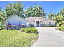 Charming single-story home with a well-manicured lawn and a curved driveway leading to the front entrance at 2410 Se 23Rd Pl, Ocala, FL 34471