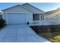 Charming single-story home with a two car garage, white picket fence, and well manicured landscaping at 627 Vagabond St, The Villages, FL 32163