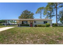 Charming single-story home featuring a covered carport and a well-maintained front yard at 10040 Sw 93Rd Ct, Ocala, FL 34481