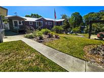 Inviting home featuring a lush lawn, garden areas and mature trees, perfect for enjoying outdoor living at 20906 River Dr, Dunnellon, FL 34431