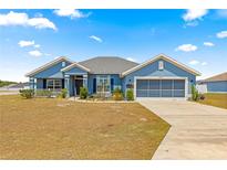 Charming single-story home featuring a beautiful blue exterior, well-manicured lawn, and an attached two-car garage at 4881 Se 91St Pl, Ocala, FL 34480