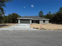 Charming single-story home featuring a gray exterior, concrete driveway, and a well-manicured lawn at 1233 Sw Winding Hills Rd, Dunnellon, FL 34431