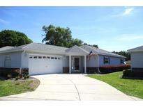 Charming single-story home featuring an attached two-car garage, American flag, and well-manicured lawn at 13675 Sw 111Th Ave, Dunnellon, FL 34432