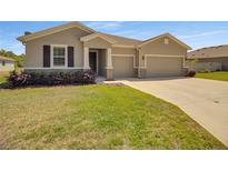 Charming home featuring a well-manicured lawn, complemented by a three-car garage at 5198 Ne 19Th Pl, Ocala, FL 34470
