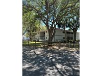 Two-story condo building with mature trees and a wood fence in a serene community at 571 Midway Trak # J202, Ocala, FL 34472
