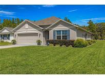 Charming single-story home featuring a well-manicured lawn and beautiful landscaping at 716 Hickory Course Loop, Ocala, FL 34472
