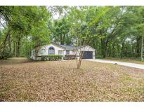 Charming single-story home featuring a well-maintained front yard and attached two-car garage in a wooded setting at 7585 Sw 79Th Pl, Ocala, FL 34476