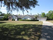 Charming single-story home featuring a well-manicured lawn, lush shrubbery, and a classic architectural design at 5355 Sw 31St St, Ocala, FL 34474