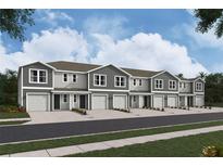 View of new two-story townhomes, showing garage, neutral paint, landscaping, and a bright sky at 6589 Sw 81St Loop, Ocala, FL 34476
