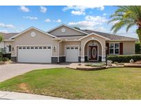 Charming single-story home featuring a well-manicured lawn, archway entrance, and three-car garage at 8955 Sw 86Th Loop, Ocala, FL 34481