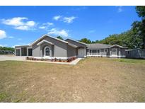 Charming gray home featuring a manicured lawn with fresh landscaping and a large garage at 9885 Se 144Th St, Summerfield, FL 34491