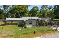 Charming single-story home with a well-maintained lawn, carport, mature trees, and a fenced yard at 1039 Ne 25Th St, Ocala, FL 34470