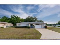 Charming single-story home featuring a well-manicured lawn, an attached two-car garage, and a neatly landscaped yard at 6150 Sw 103Rd Loop, Ocala, FL 34476