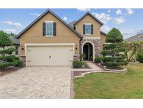 Charming two-story home featuring a brick driveway, manicured lawn, and stone accents on the facade at 6816 Sw 95Th Cir, Ocala, FL 34481