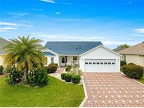 Charming single-story home featuring a brick driveway, manicured landscaping, and a well-maintained lawn at 2087 Bonneau Ln, The Villages, FL 32162