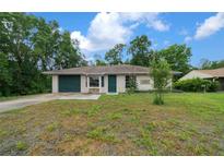 Charming single-story home featuring an attached garage, manicured lawn, and lush, mature trees at 21168 Sw Peach Blossom St, Dunnellon, FL 34431