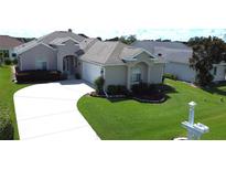 Charming home with a well-manicured lawn, lush landscaping, and a curved driveway leading to an attached two car garage at 2323 Nw 55Th Avenue Rd, Ocala, FL 34482