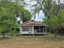 Charming single-story home featuring a screened-in porch and surrounded by mature trees and a weathered fence at 823 Ne 4Th St, Ocala, FL 34470