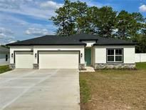 Beautiful single story home featuring an attached three-car garage and well-maintained lawn at 13081 Sw 78Th Cir, Ocala, FL 34473