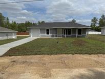Charming single-story home featuring a manicured lawn, attached garage, and inviting front entrance at 14437 Sw 21St Pl, Ocala, FL 34481