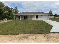 Charming single-story home with a fresh lawn, inviting front porch, and attached garage at 21 Pl # 14443, Ocala, FL 34481