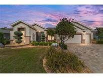 Charming home featuring manicured landscaping, mature trees, and a brick driveway at 7455 Sw 97Th Terrace Rd, Ocala, FL 34481