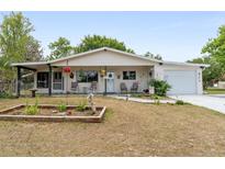 Charming single-story home with a covered front porch, manicured lawn, and attached garage at 9940 Sw 103Rd Pl, Ocala, FL 34481