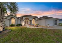 Charming single-story home with arched windows, well-maintained lawn, and beautiful landscaping at sunset at 5245 Nw 21St Loop, Ocala, FL 34482