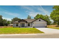 Charming single-story home featuring a two-car garage, well-manicured lawn, and welcoming front entrance at 112 Juniper Run, Ocala, FL 34472