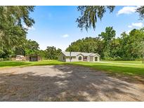 Charming single-story home featuring a spacious lot with lush trees and a gravel driveway at 14171 Sw 8Th Ave, Ocala, FL 34473