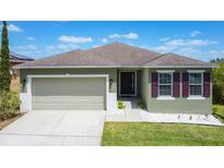 Charming single-story home featuring a well-manicured lawn, two-car garage, and decorative window shutters at 4013 Ruby Run, Haines City, FL 33844
