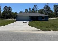 Charming single-story home with a well-manicured lawn, attached two-car garage, and a concrete driveway at 4424 Sw Viola Ct, Dunnellon, FL 34431