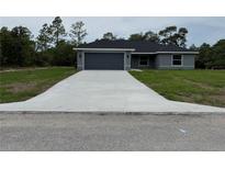Charming single-story home with a gray exterior, attached garage, and a well-manicured lawn at 4424 Sw Viola Ct, Dunnellon, FL 34431