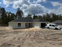 Charming single-story home featuring a spacious driveway and attached garage, surrounded by lush greenery at 4454 Sw Viola Ct, Dunnellon, FL 34431