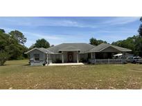 Charming single-story home featuring a covered porch, well-manicured lawn, and an inviting red front door at 4981 Ne 110Th Street Ne St, Anthony, FL 32617