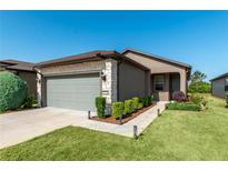Charming home featuring a stone facade, two-car garage, landscaped yard, and a sidewalk leading to the front door at 6132 Sw 94Th Ter, Ocala, FL 34481