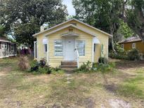 Quaint yellow bungalow with white trim, complemented by lush greenery and a welcoming front porch at 621 Ne 20Th St, Ocala, FL 34470