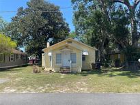 Charming, light yellow, one-story home with a well-maintained lawn and a classic white front door at 621 Ne 20Th St, Ocala, FL 34470