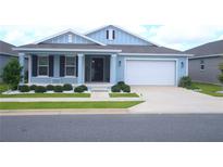 Charming blue home featuring a well-manicured lawn, white rock landscaping, and an attached two-car garage at 7429 Sw 61St St, Ocala, FL 34474