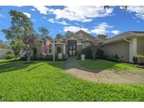 Charming single-story home with a lush green lawn, beautiful landscaping, and a welcoming walkway to the front door at 811 Se 49Th Ave, Ocala, FL 34471