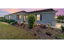 Charming single story home with a manicured lawn and a beautiful flower garden at sunset at 8693 Sw 76Th Ln, Ocala, FL 34481