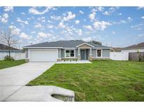 Charming single-story home featuring stone accents, a well-manicured lawn, and a two-car garage at 20751 Sw Cardinal Ave, Dunnellon, FL 34431